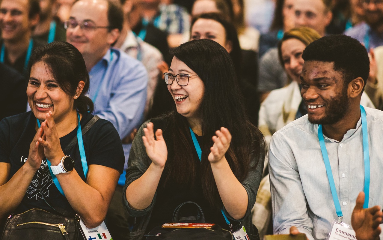 Two women and a man applaud with big smiles for a customer presentation at Tableau Conference Europe.